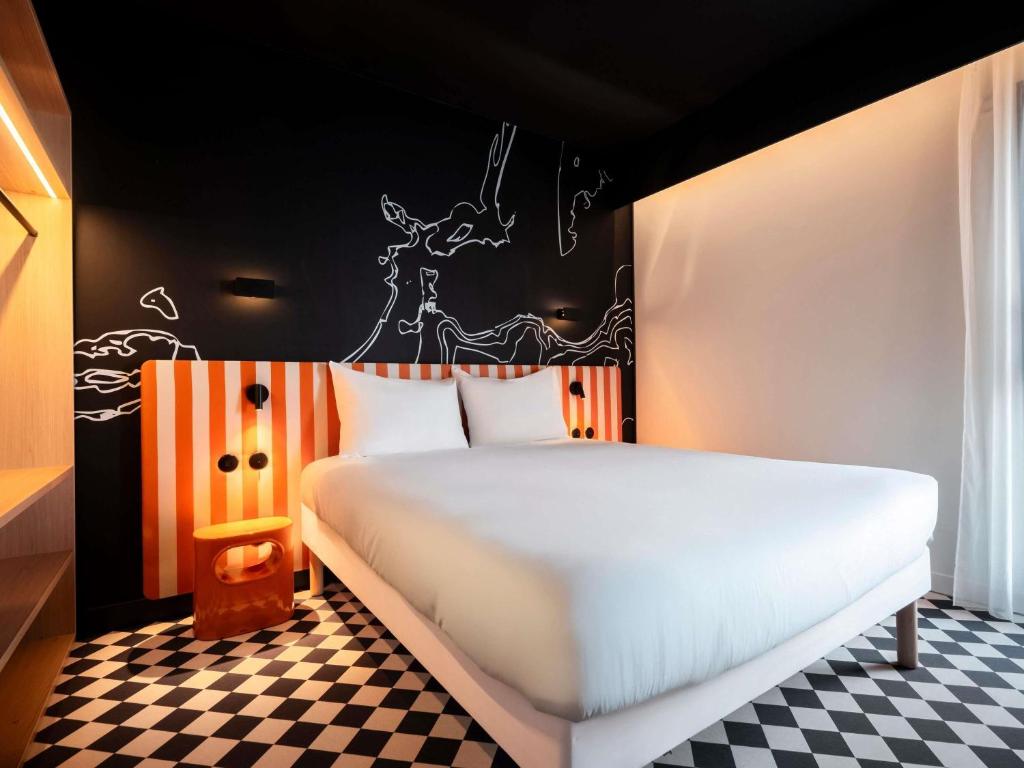 a bedroom with a white bed with a checkered floor at ibis Styles La Rochelle Centre les Minimes in La Rochelle