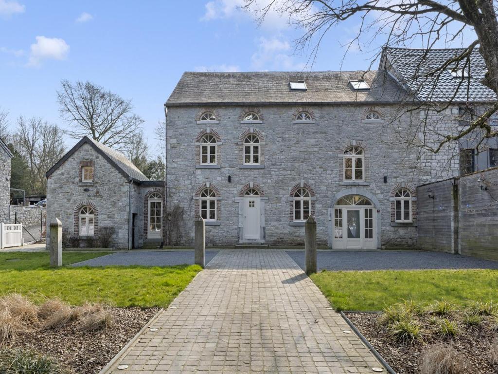 a large stone house with a brick driveway at Mansion in Aywaille with sauna in Aywaille