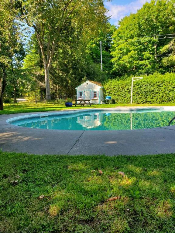 a swimming pool with a house in the background at Falcon Retreats in Sharbot Lake
