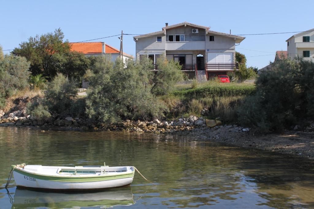 a small boat in the water in front of a house at Studio Nevidjane 8401a in Neviđane