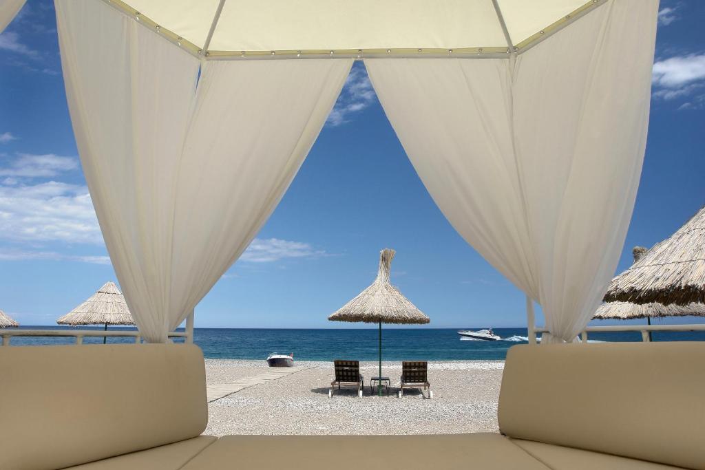 una playa con sombrillas y sillas y el océano en Olympos Lodge, en Cıralı