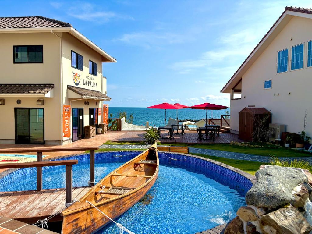 a wooden boat sitting in a pool next to a building at Love&Peace Resort in Shima