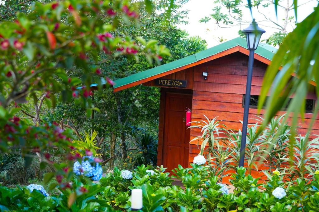 a small red house with a green roof in a garden at Eco Granja Don Lolo in Quesada