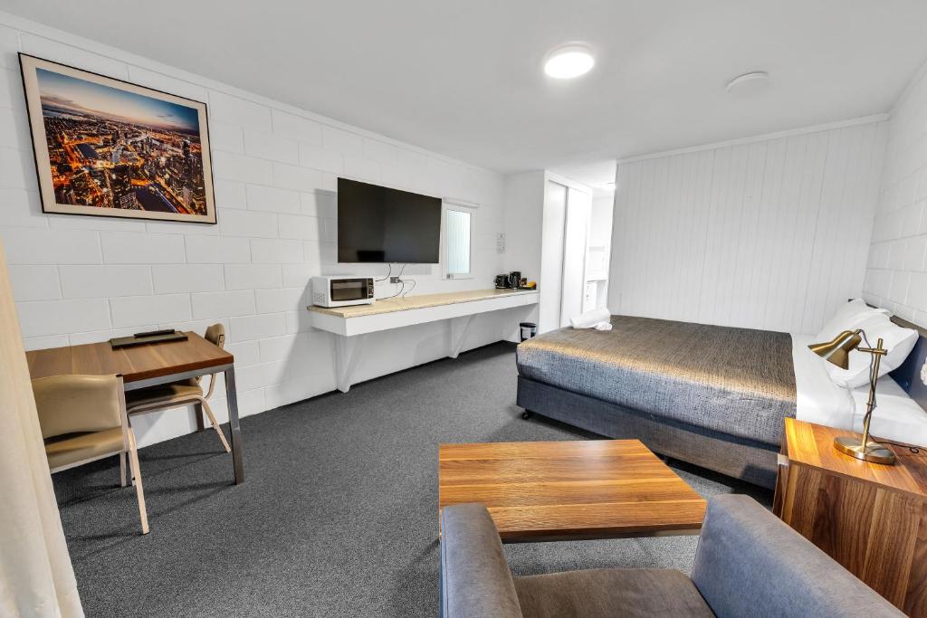 a hotel room with a bed and a couch and a table at Bendigo Motor Inn in Bendigo