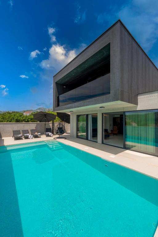 a large swimming pool in front of a house at Luxury Villa Black Cube with Heated pool in Mlini