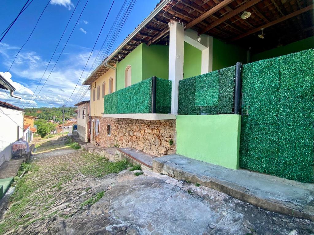 a building with a green fence next to a street at Visite Chapäda Hospedaria in Lençóis