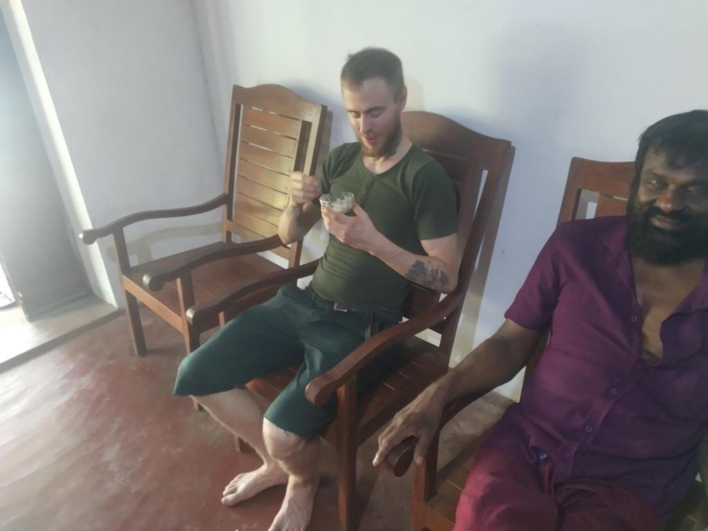 two men sitting in chairs looking at a cell phone at ADOBE AFFECTIOn in Tangalle