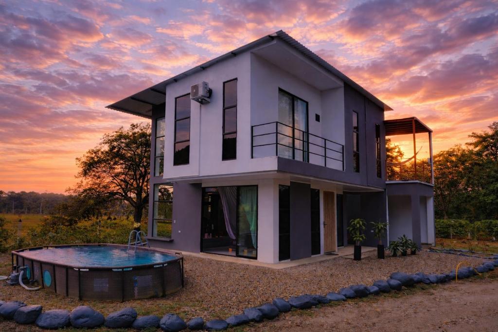 a house with a pool in front of a sunset at Cabaña Moderna a 1km del Centro de Tauramena in Tauramena