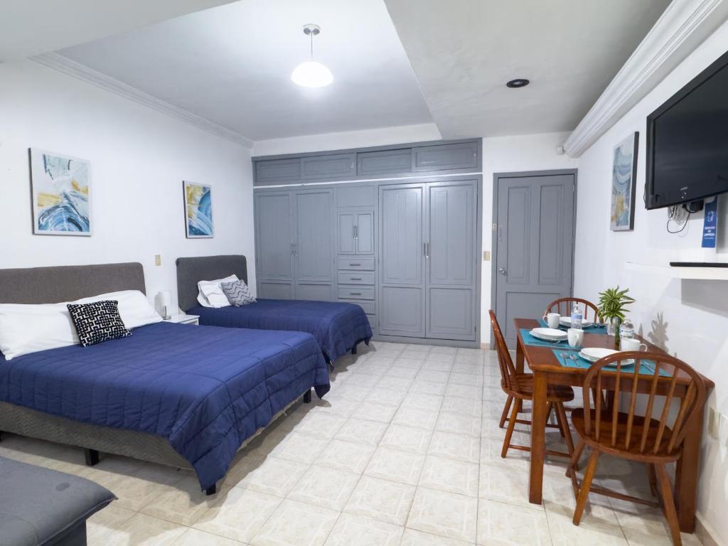 a bedroom with two beds and a table and a tv at Casa San Luis in Tuxtla Gutiérrez