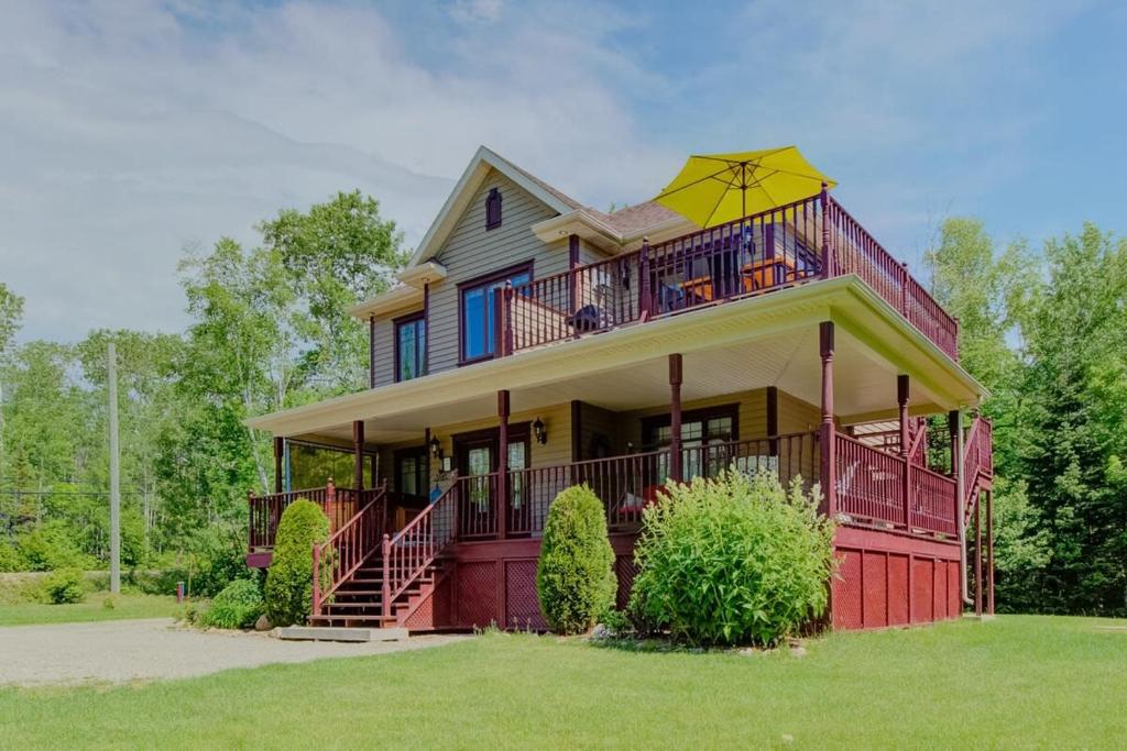 a large house with an umbrella on top of it at L'Escapade - Spa billard & foyer in Petite-Rivière-Saint-François