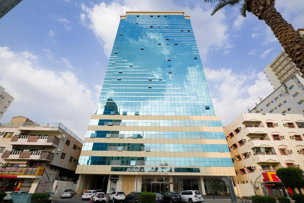 a tall glass building with cars parked in front of it at فندق الخلفاء الماسى الفندقيه in Mecca