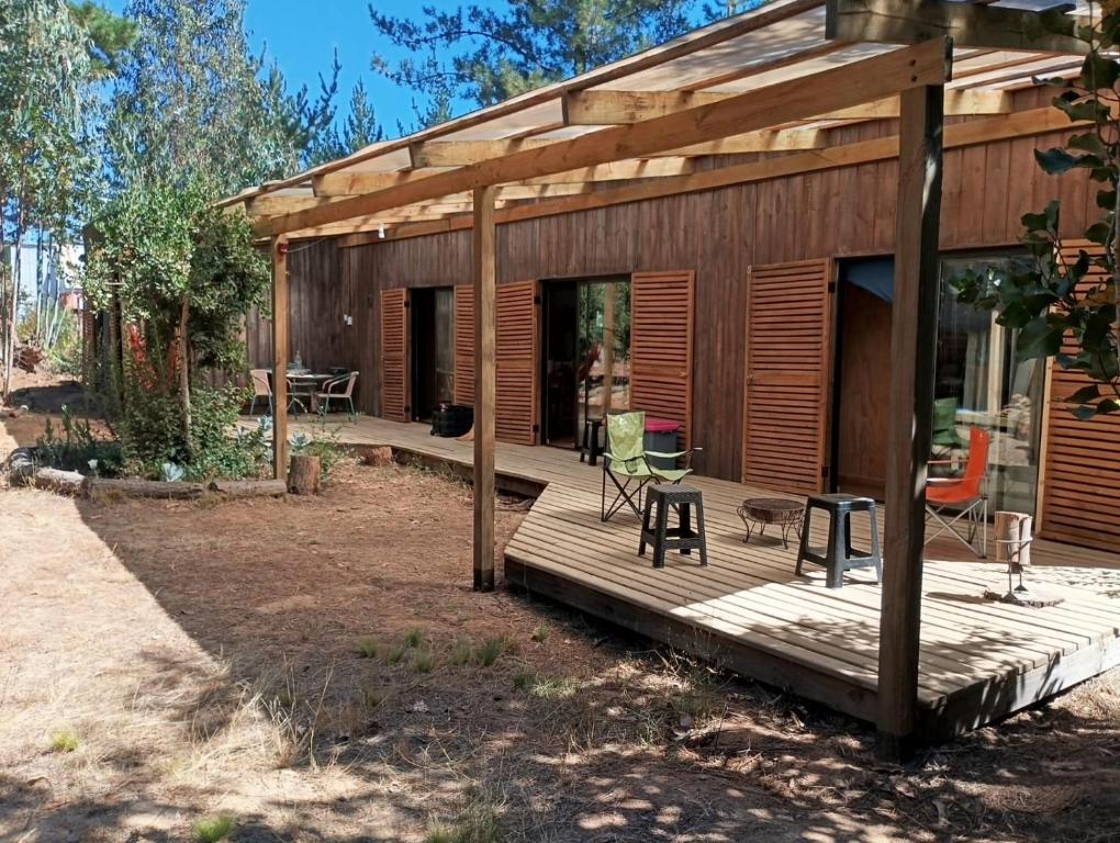 a house with a wooden deck with a chair on it at Cabaña Bosque Tumán in Pullingue