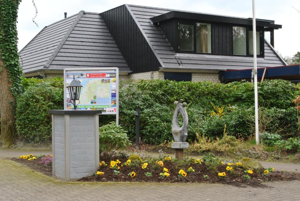 uma casa com uma estátua e flores à sua frente em Park De Haeghehorst em Ermelo