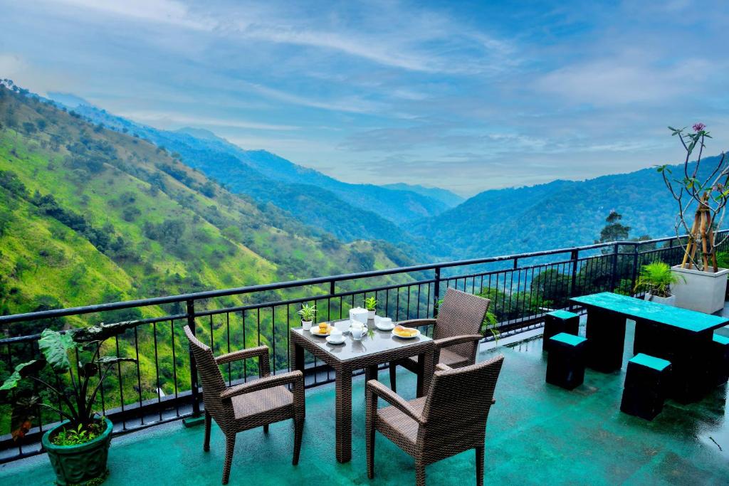 a table and chairs on a balcony with a view of mountains at Ella Mount Heaven in Ella