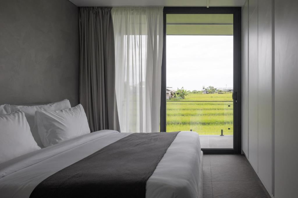 a bedroom with a large bed and a large window at UNIT Nuanu Village in Canggu