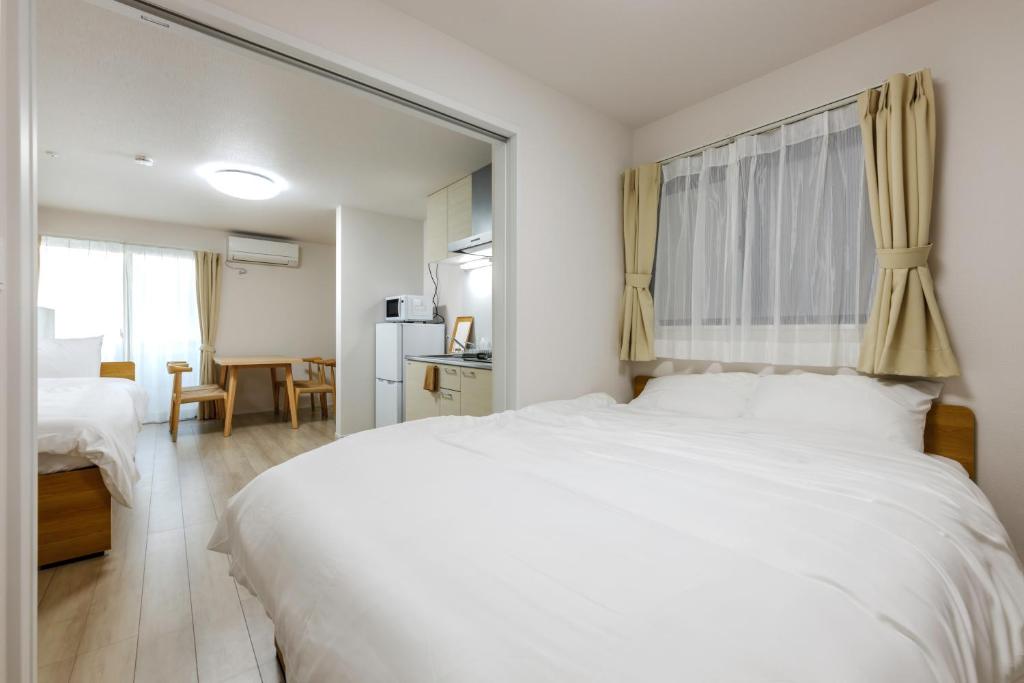 a bedroom with a large white bed with a mirror at Anecis笠取町1 in Nagoya