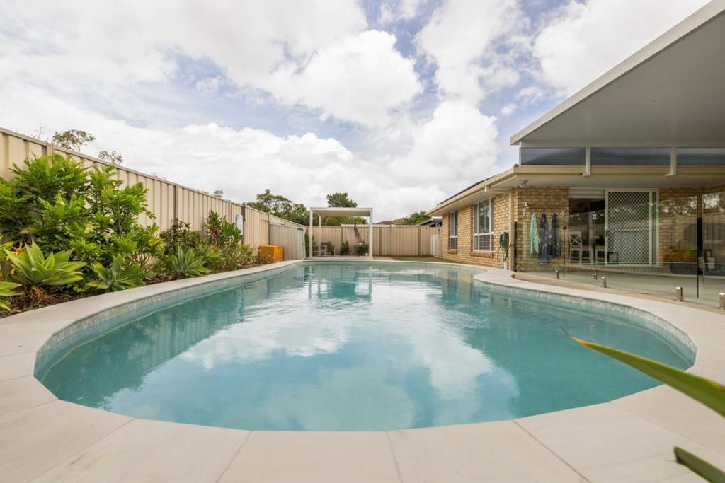 a swimming pool in front of a house at The Salty Anchor in Banksia Beach