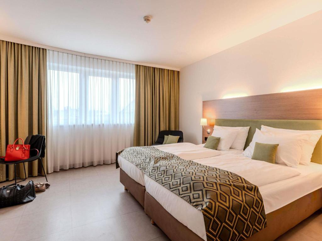 a hotel room with a large bed and a window at Hotel Mercure Graz City in Graz