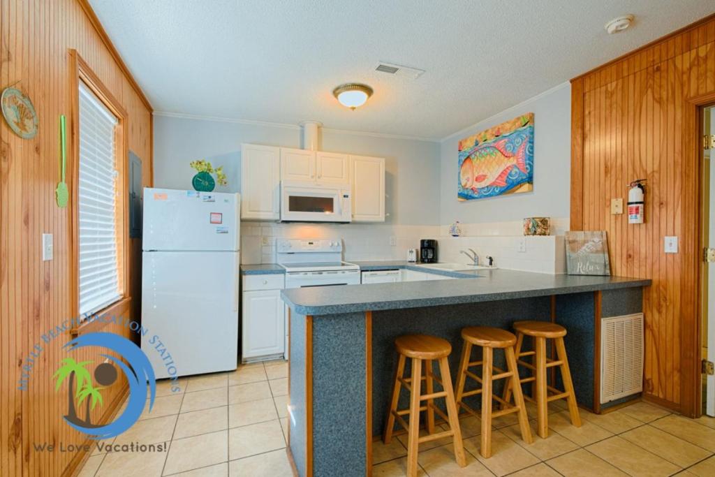 a kitchen with white appliances and a counter with stools at Cg Beach Bungalow #3 in Myrtle Beach