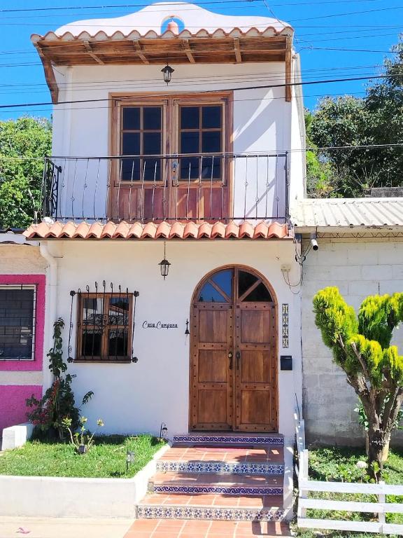 a house with a wooden door and a balcony at Casa Campana in Concepción de Ataco