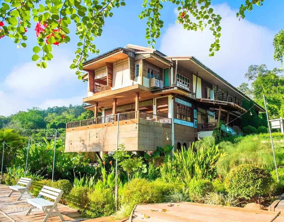a house on a hill with benches in front of it at Sang Poy Cottage in Ban Kung Mai Sak
