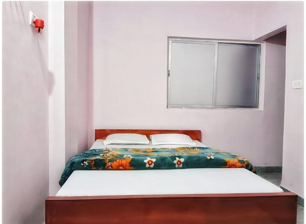 a bedroom with a bed with a floral bedspread and a window at Sri Hotel Ganga Couple&Family Friendly in Patna