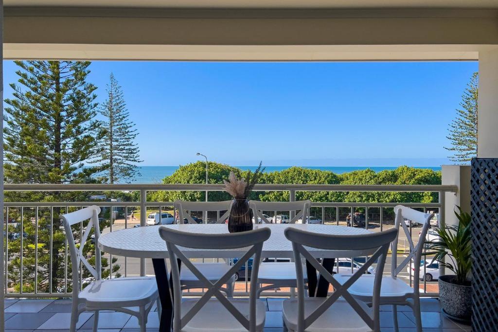 a table and chairs on a balcony with a view of the ocean at Alex Beach Front Nest in Alexandra Headland