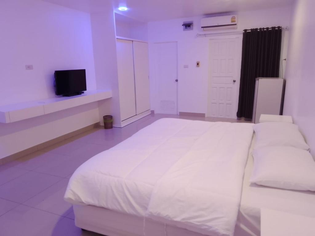 a white bedroom with a large bed and a tv at Illusion Hostel & Club in Pattaya South