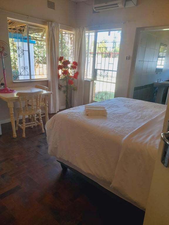a bedroom with a bed and a table and windows at Dne Blue Star in Klerksdorp