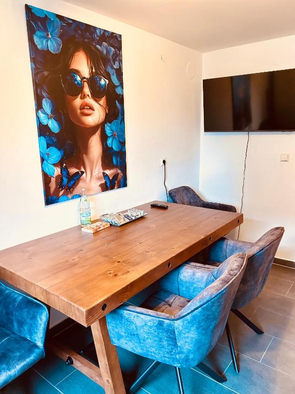 a wooden table with blue chairs and a painting on the wall at Apartments Yvonne Sigg in Rust