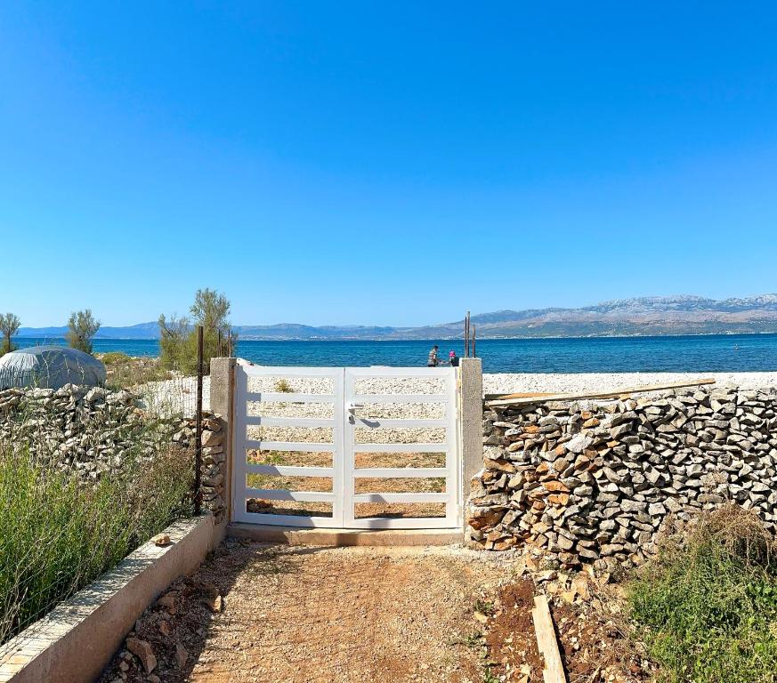 a white fence next to a stone wall and water at Mirca by the Sea in Mirce