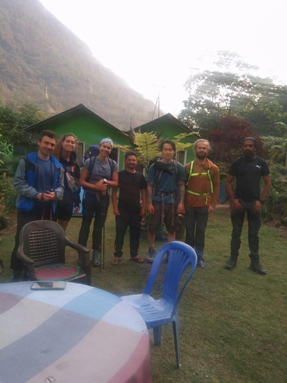 a group of people standing next to a table at Riverside hostel in Ghanpokhara