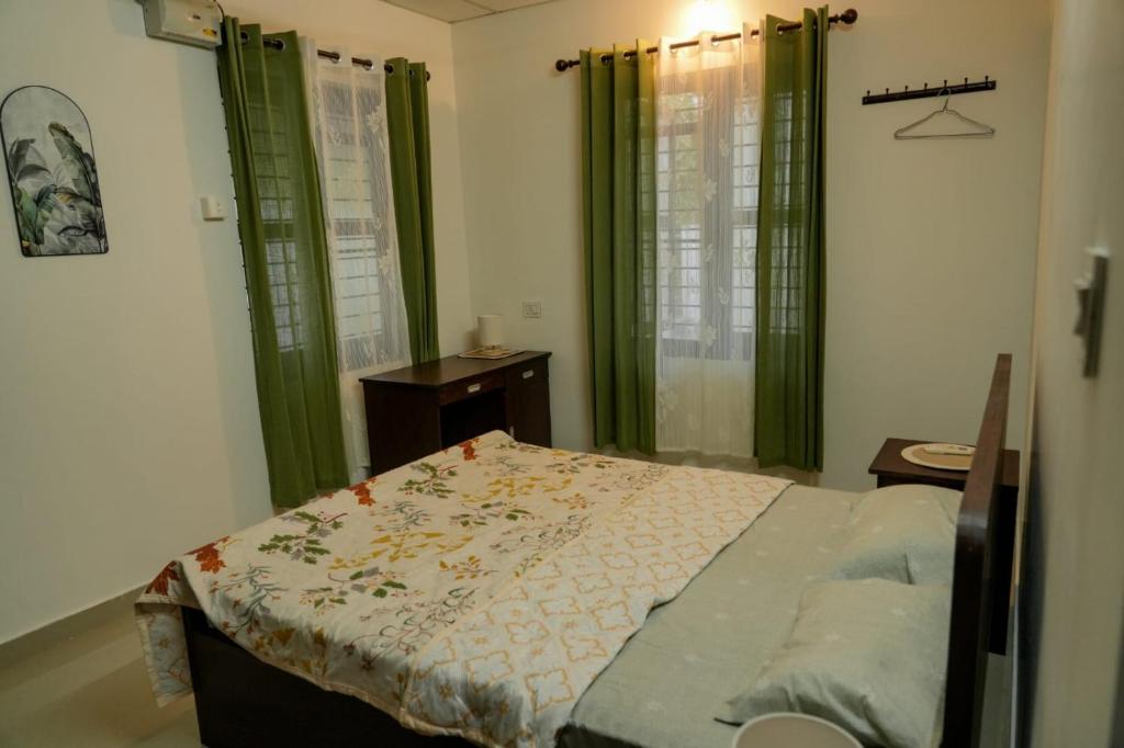 a bedroom with a bed with green drapes at Neerbhoomi in Kollam