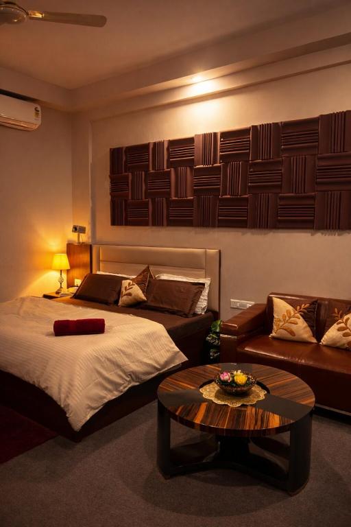 a bedroom with a bed and a couch and a table at Midnight Atelier in Greater Noida