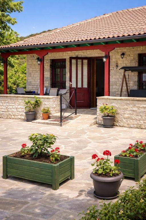 a patio with two planters with flowers in front of a house at Λαμπρινής Guest House-Zagori in Asprangeloi