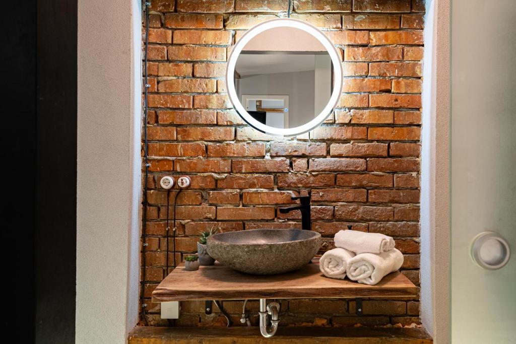 a bathroom with a sink and a mirror on a brick wall at ARI Central Location in Arad
