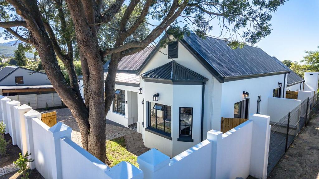 a white house with a fence and a tree at The Wellington Residence in George