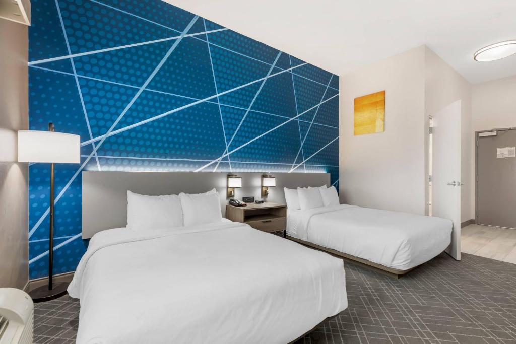 a hotel room with two beds and a blue wall at Comfort Inn Ballard-Roosevelt in Roosevelt