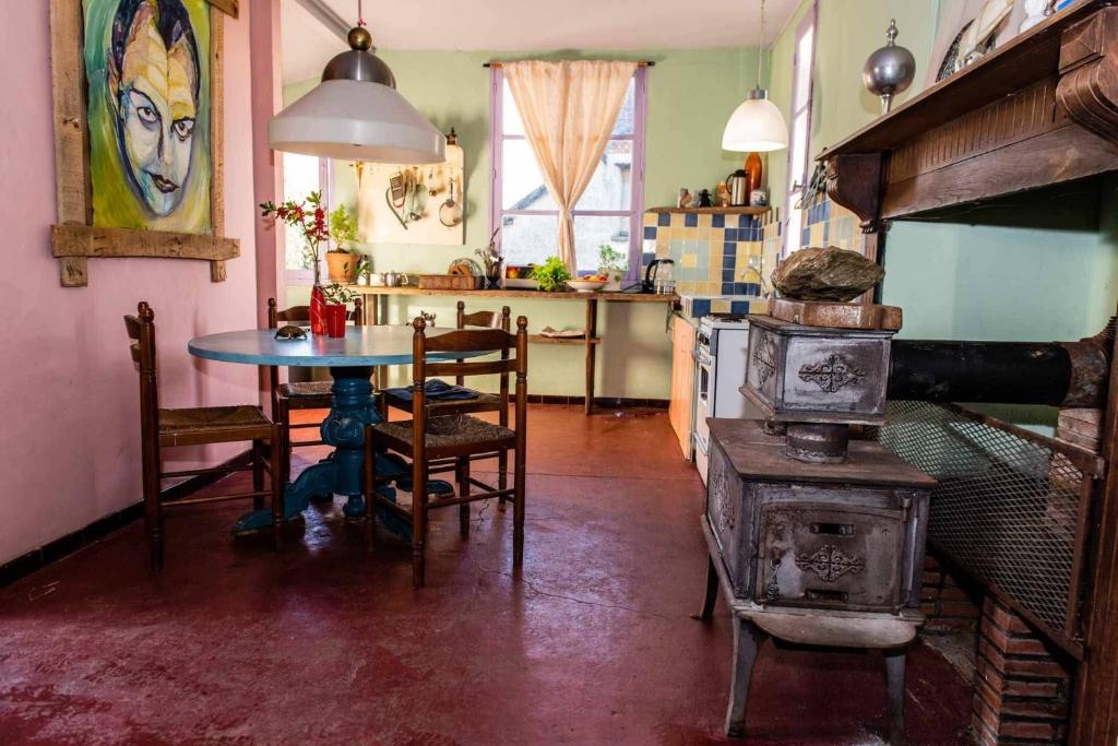 a kitchen with a table and a stove in a room at petite maison artistique in Saint-Plantaire