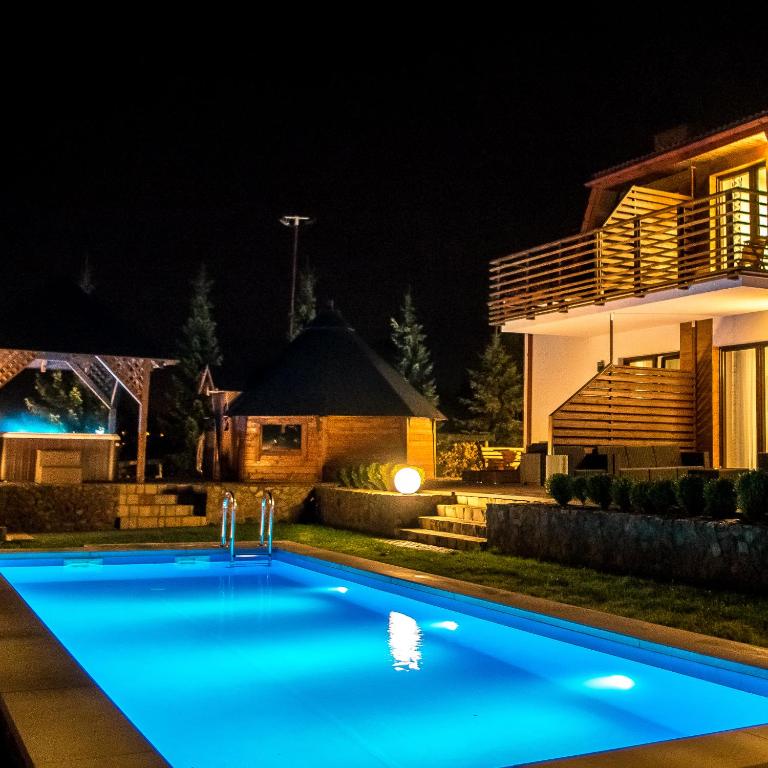 a swimming pool in front of a house at night at Apartamenty Pod Łysicą & SPA - przy stoku, basen, jacuzzi, sauna in Krajno Pierwsze