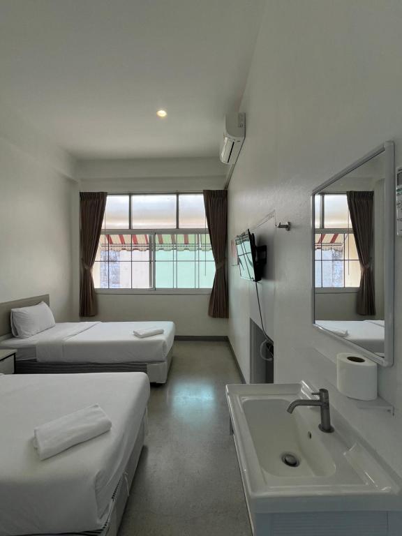 a room with two beds and a sink and a mirror at Muangchan Hotel in Chanthaburi