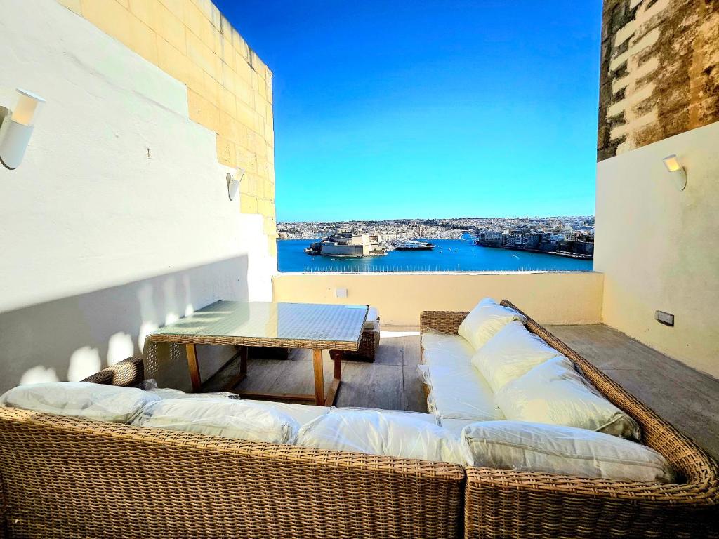 a balcony with a table and wicker couch at Portus Noir Valletta in Valletta