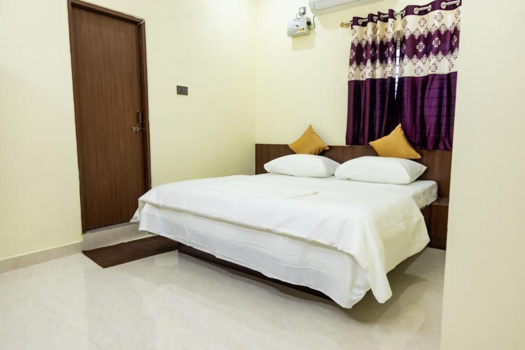 a bedroom with a bed with white sheets and yellow pillows at SKS Residensy in Kāraikkudi