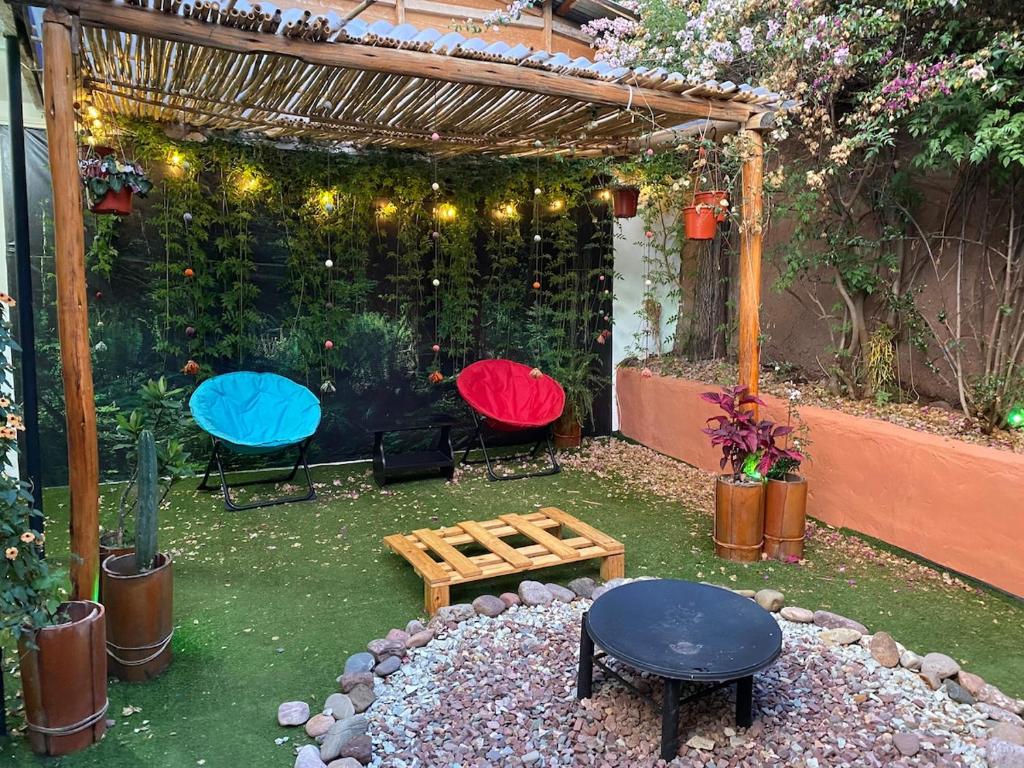 a garden with three chairs and a pergola with lights at Authentic Peruvian home with gorgeous patio in Pisac