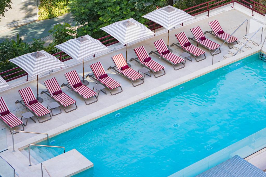 a group of chairs and umbrellas next to a pool at Hesperia Sevilla in Seville