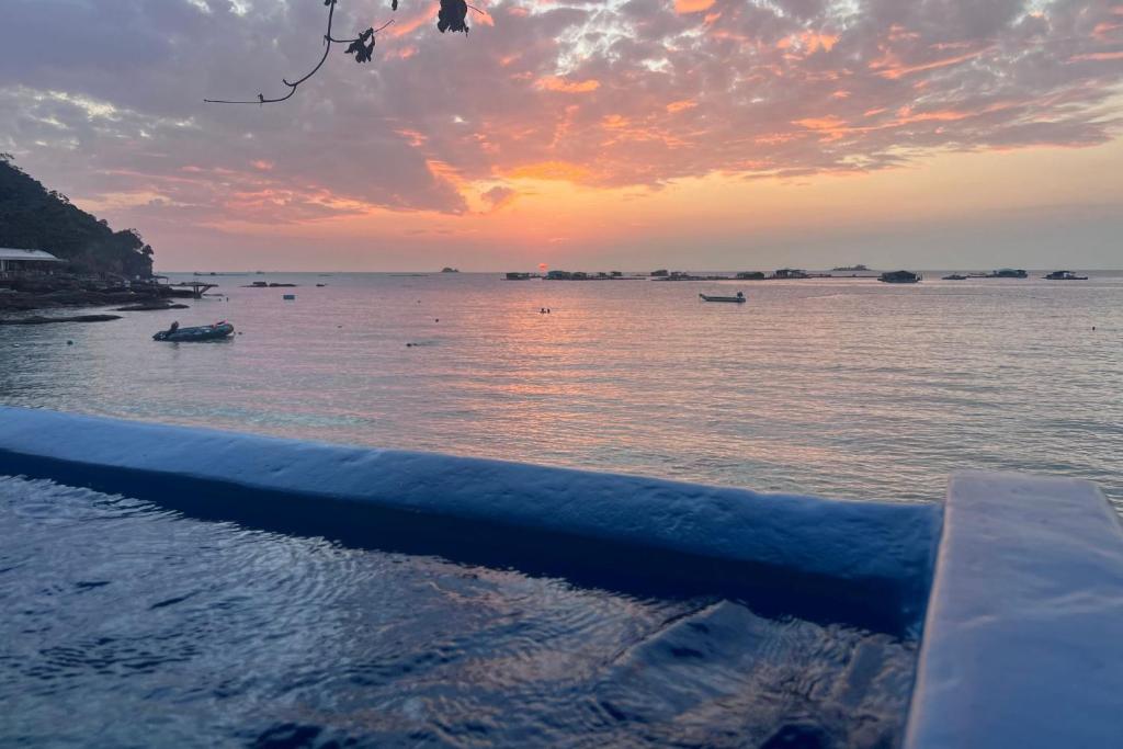 a sunset over the water with boats in the water at Anchovy Beachfront Villas in Phú Quốc