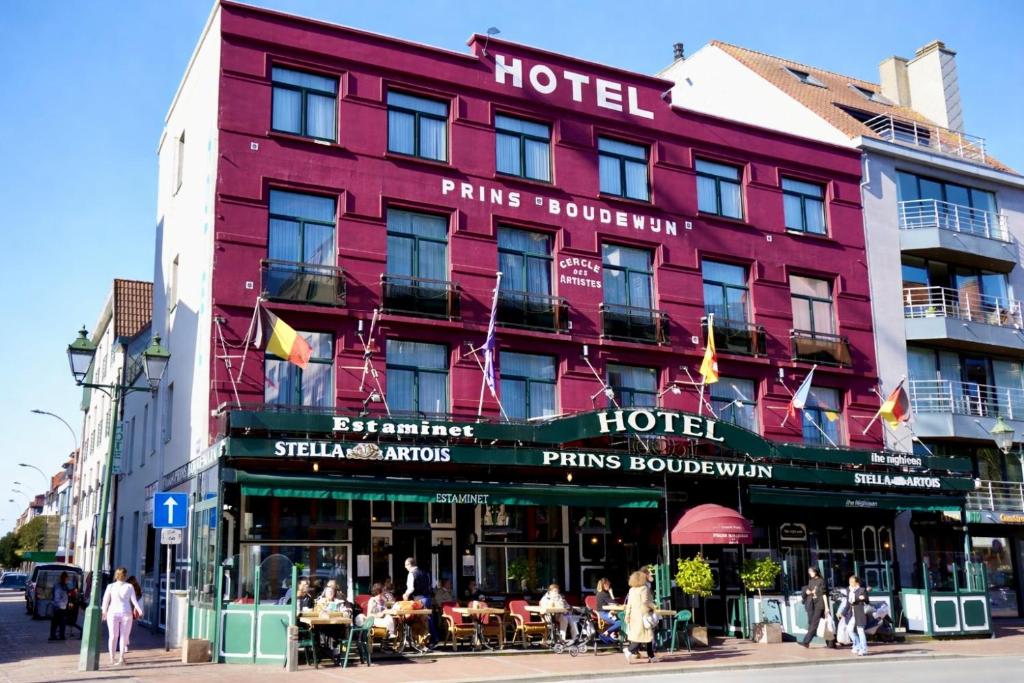 a red building with people sitting outside of it at Hotel Prins Boudewijn in Knokke-Heist