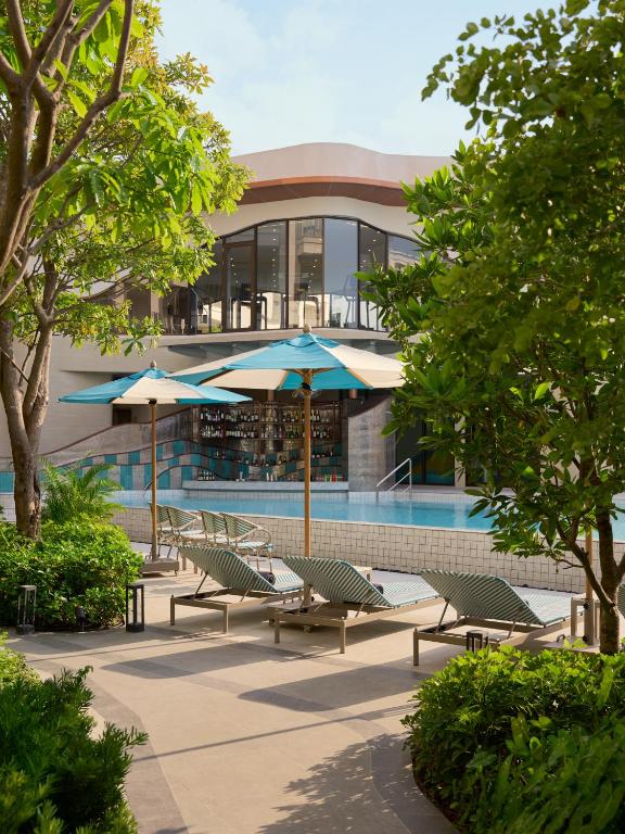 a pool with chairs and umbrellas in front of a building at Marni Pattaya in Pattaya South