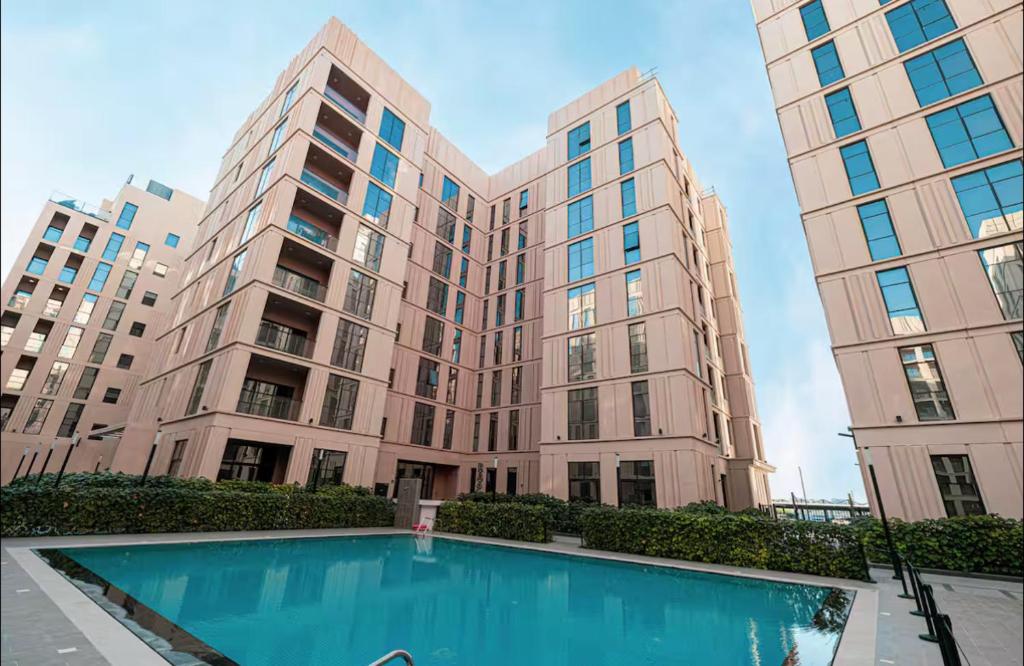 a large building with a swimming pool in front of it at Modern studio with pool and fiber connection in Sharjah