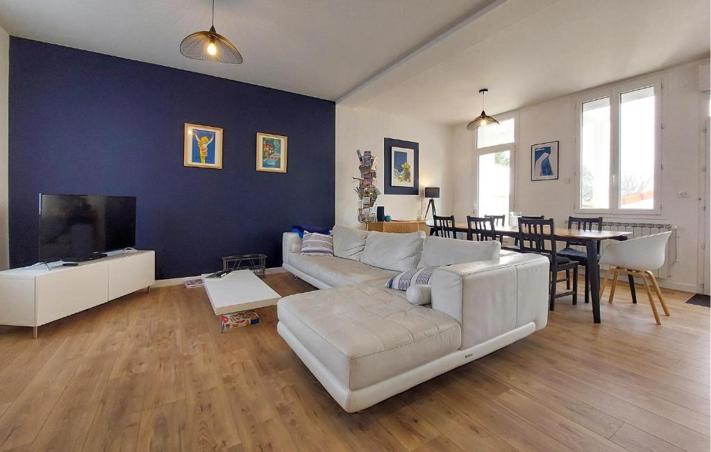 a living room with a white couch and a tv at Charmante Maison Proche Mer in Royan